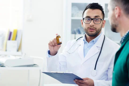 lekarz trzymający tabletki esperalu poleca zabieg zaszycia alkoholowego